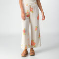 Front view of Belladona Pant in white with floral print, paired with tan platform sandals for beach-inspired comfort.