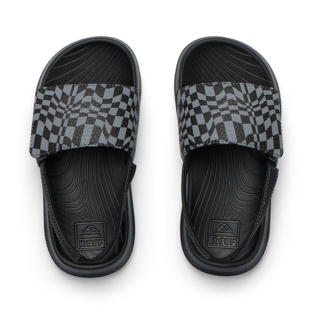 Pair of Little Salty Slide sandals for boys facing up, featuring black checker pattern and anatomical arch support.