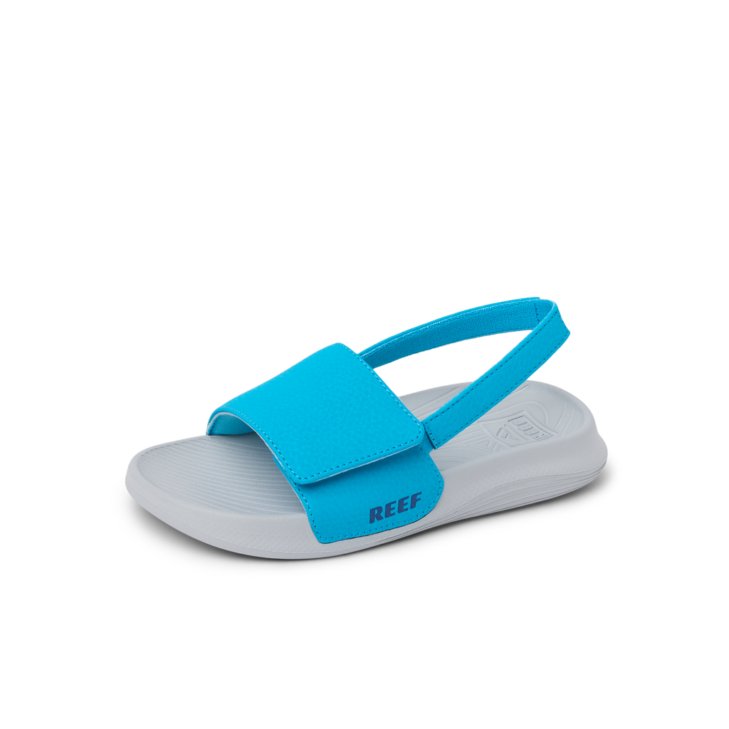 Little Salty Slide sandal facing right, showing front and side in blue with anatomical arch support and cushioned sole.