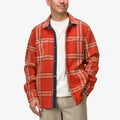 Man wearing orange and red plaid Karter Shirt Jacket facing forward in a relaxed pose, showcasing front and sleeve details.
