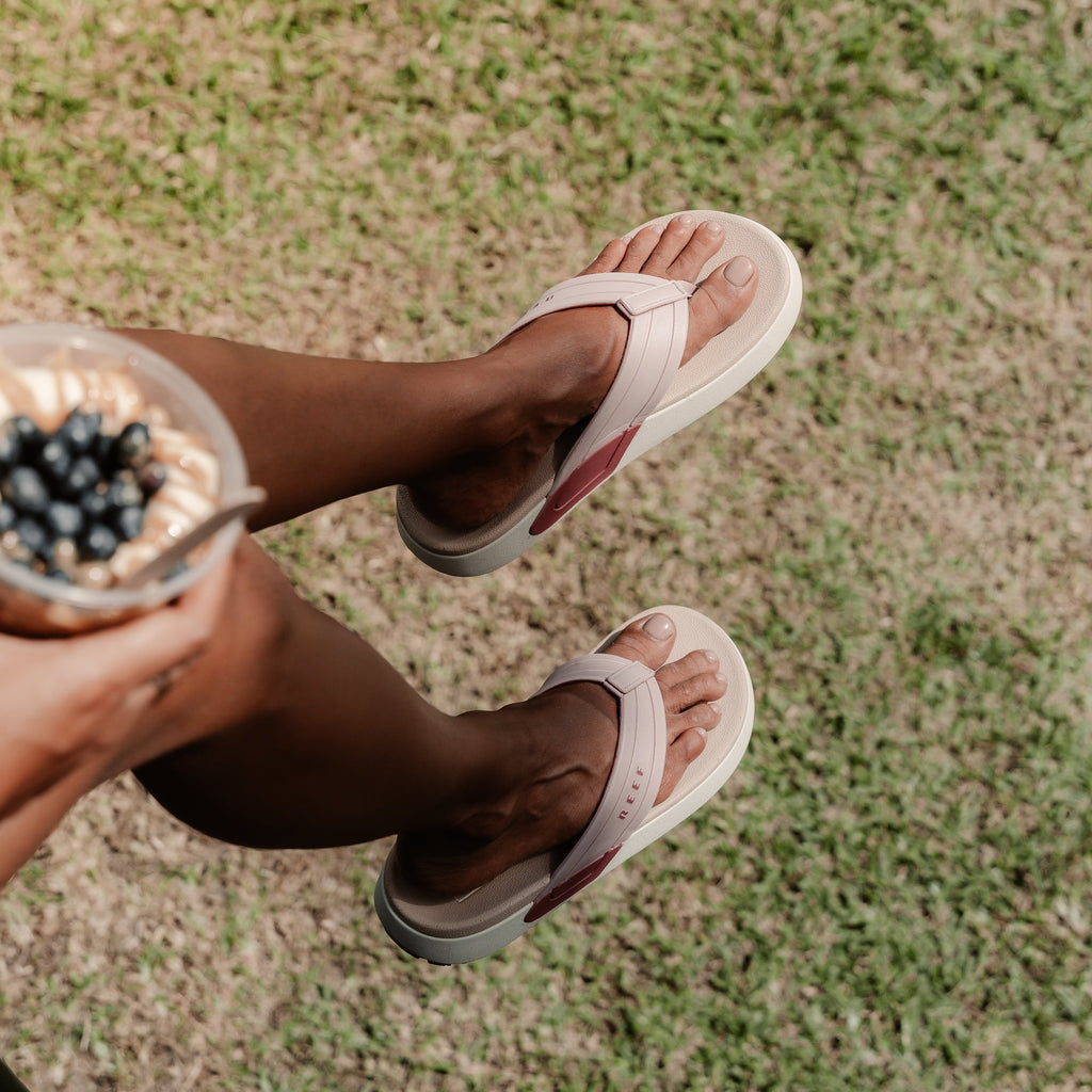 woman wearing SYDNEE SWELL LOW PALE MAUVE and sitting by some grass holding a fruit bowl